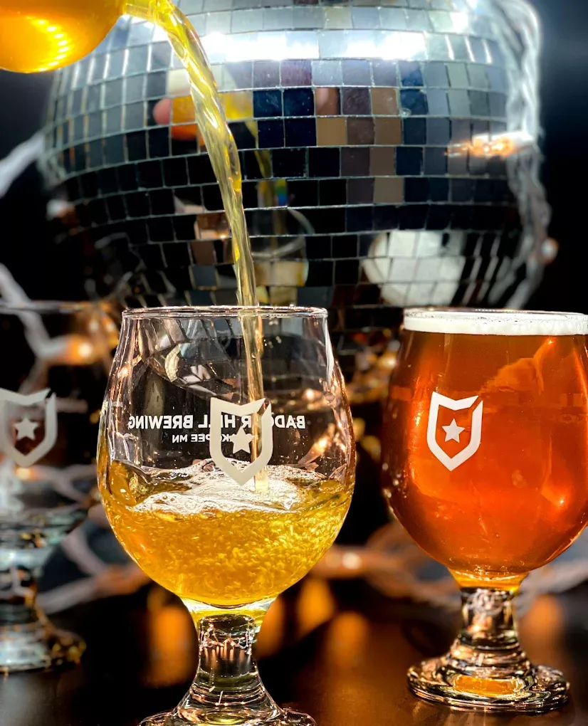 A view of a mug filled with beer and another glass being filled with beer.