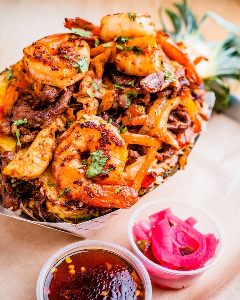 A large bowl full of shrimp and other fixings, along with a side of cocktail sauce and onion on the side.