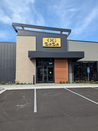An outdoor view of a restaurant with a modern style in beige and black colors with a yellow sign above the door.
