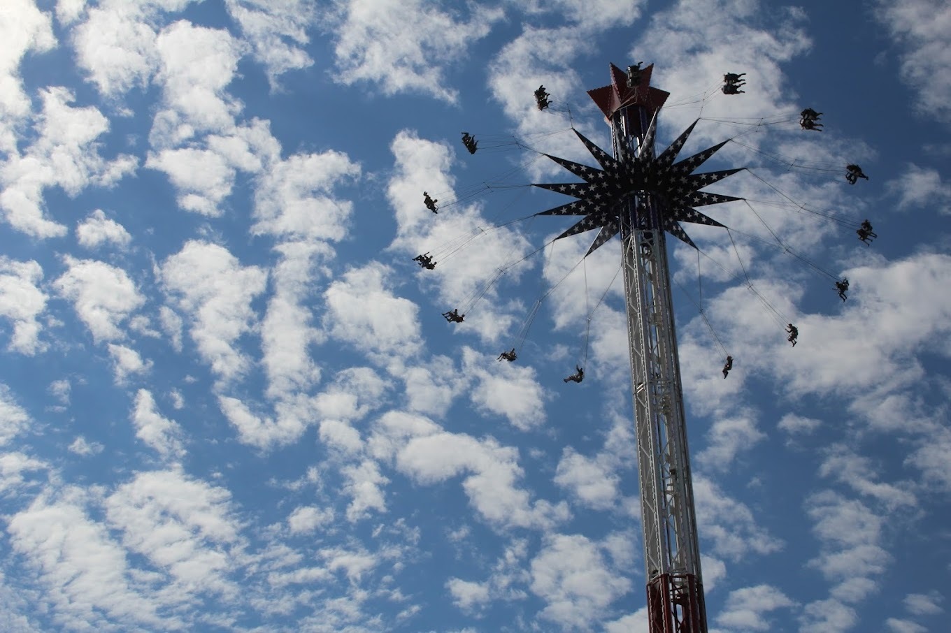 A view of a large amusement ride with a view of the sky and clouds in the background.