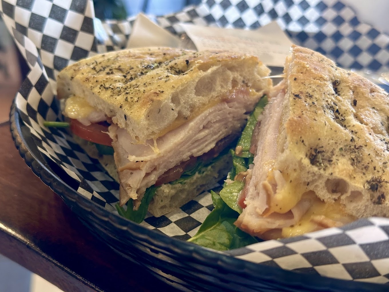 A view of a sandwich with meat, tomato, lettuce all in a delicious herb bread.
