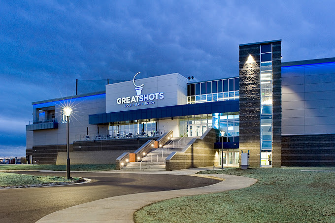 Nighttime exterior view of a sleek building with a large set of stairs and lots of illuminated lighting.