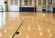 Bright indoor basketball court featuring polished hardwood flooring, crisp court markings, basketball hoops, and large windows filling the space with natural light.