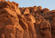 Towering red sandstone rock formations with weathered textures and rugged desert scenery beneath a clear blue sky.