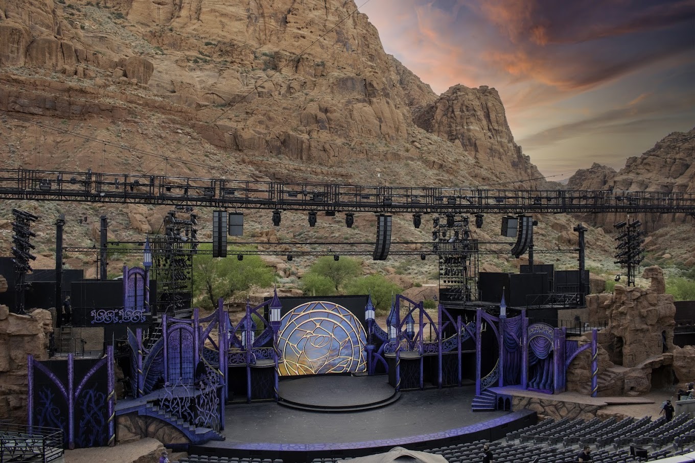 A stage in the middle of a large canyon with a colorful sunset in the background.