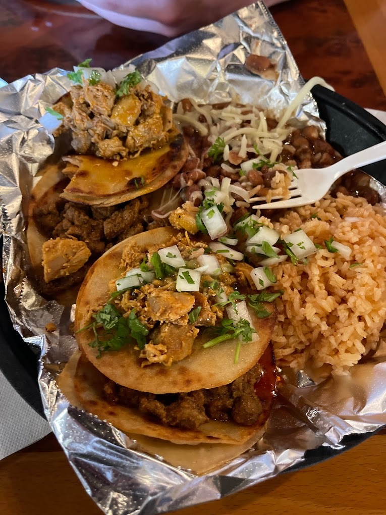 A plate of house made street tacos and rice with foil to cover the base of the plate.