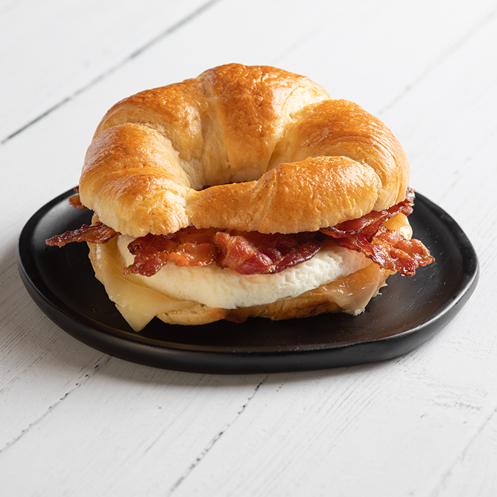 A croissant breakfast sandwich on a black plate.
