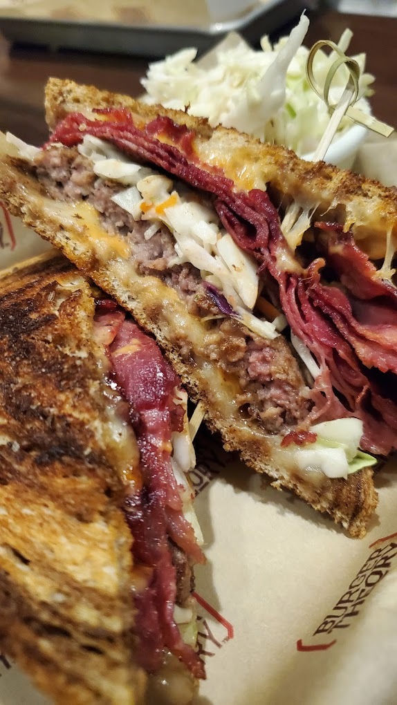 A white plate with a Rueben sandwich sliced in half.