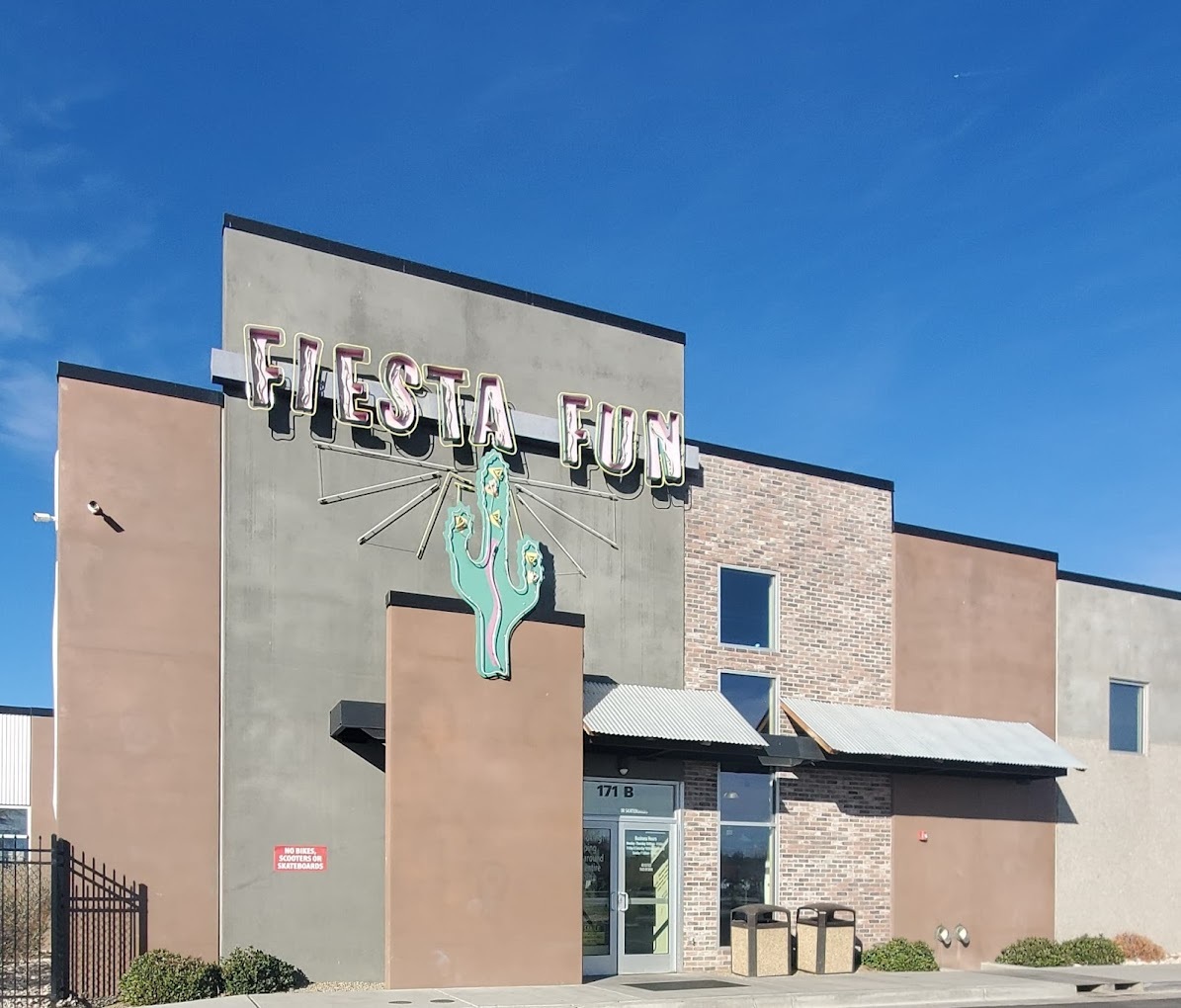 A beige and gray building with a large lighted cactus and a sign that reads "Fiesta Fun" in a a white western font.