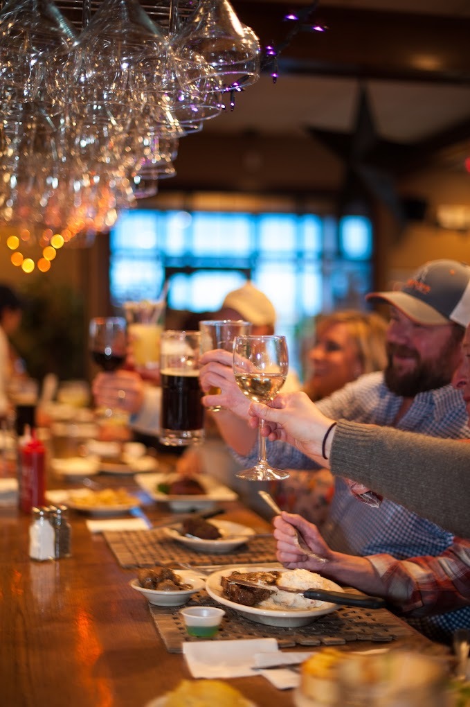 Group of friends at a bar cheering with their beers and cocktails.