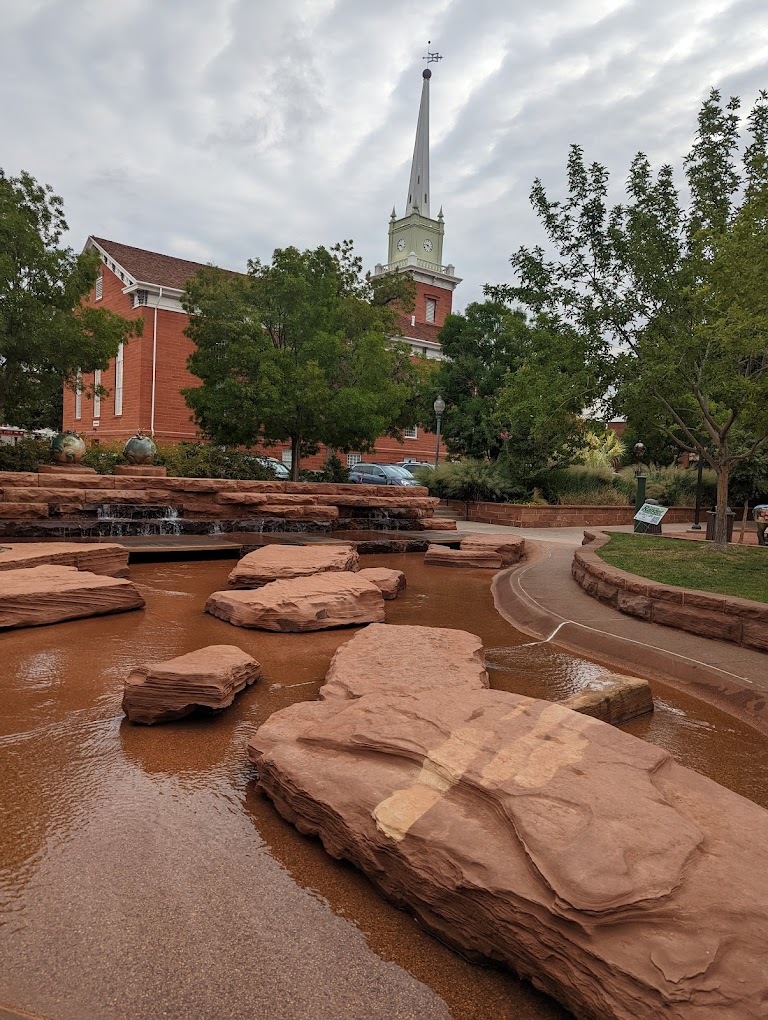 A cloudy background with a large pointed structure, a splash park in the foreground with water rock features.