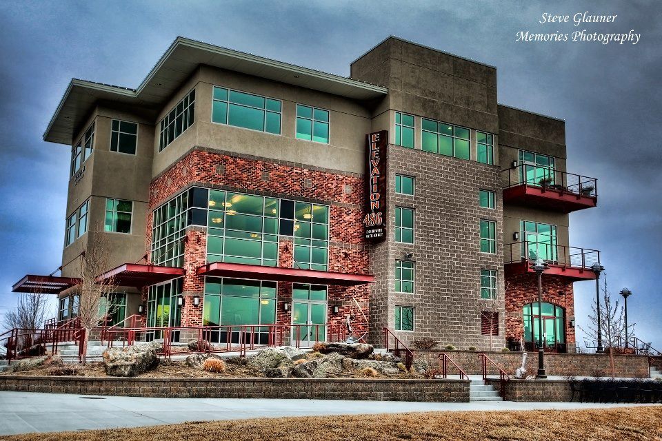 A large brown and tan building with lots of glass windows and awnings on the windows.