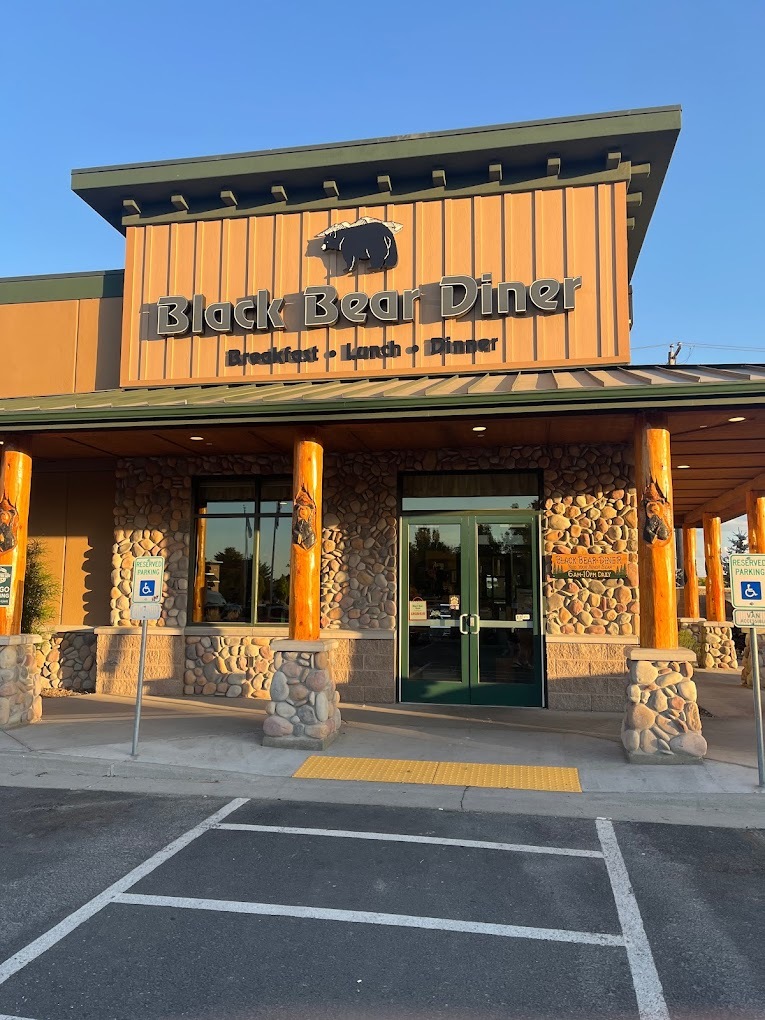 A brown building with stone accenting, an awning covers the door, above the awning is signage reading "Black Bear Diner"