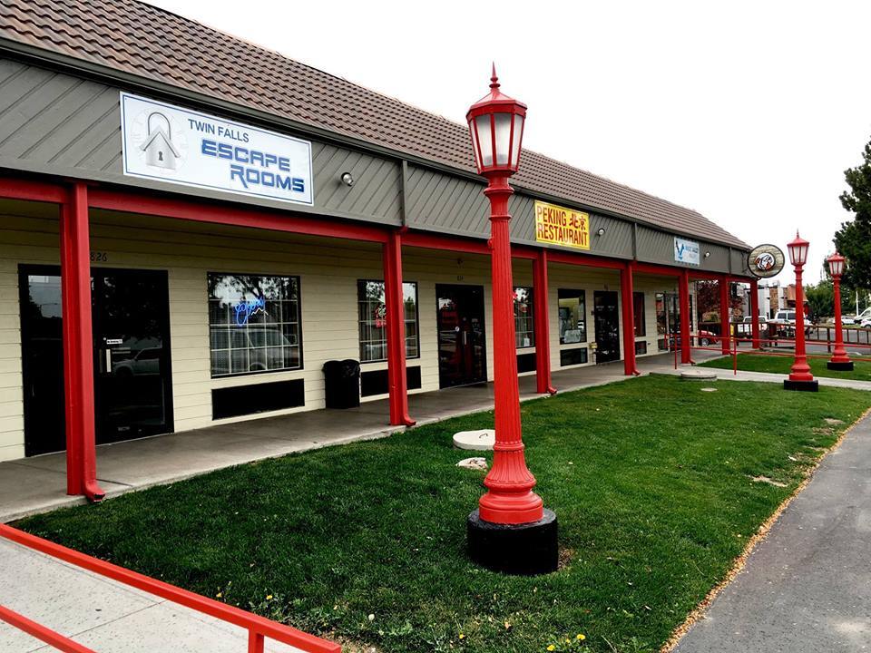 An outside view of a strip mall with red accenting and red light posts out front.