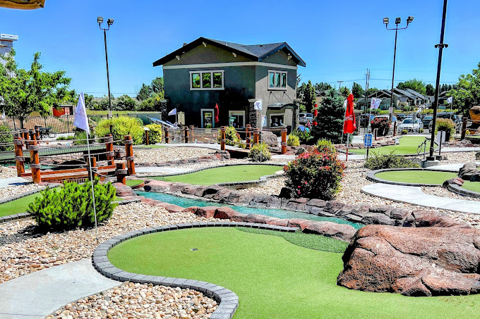 An view of an outside mini-golf course with an small water feature river and bridge.