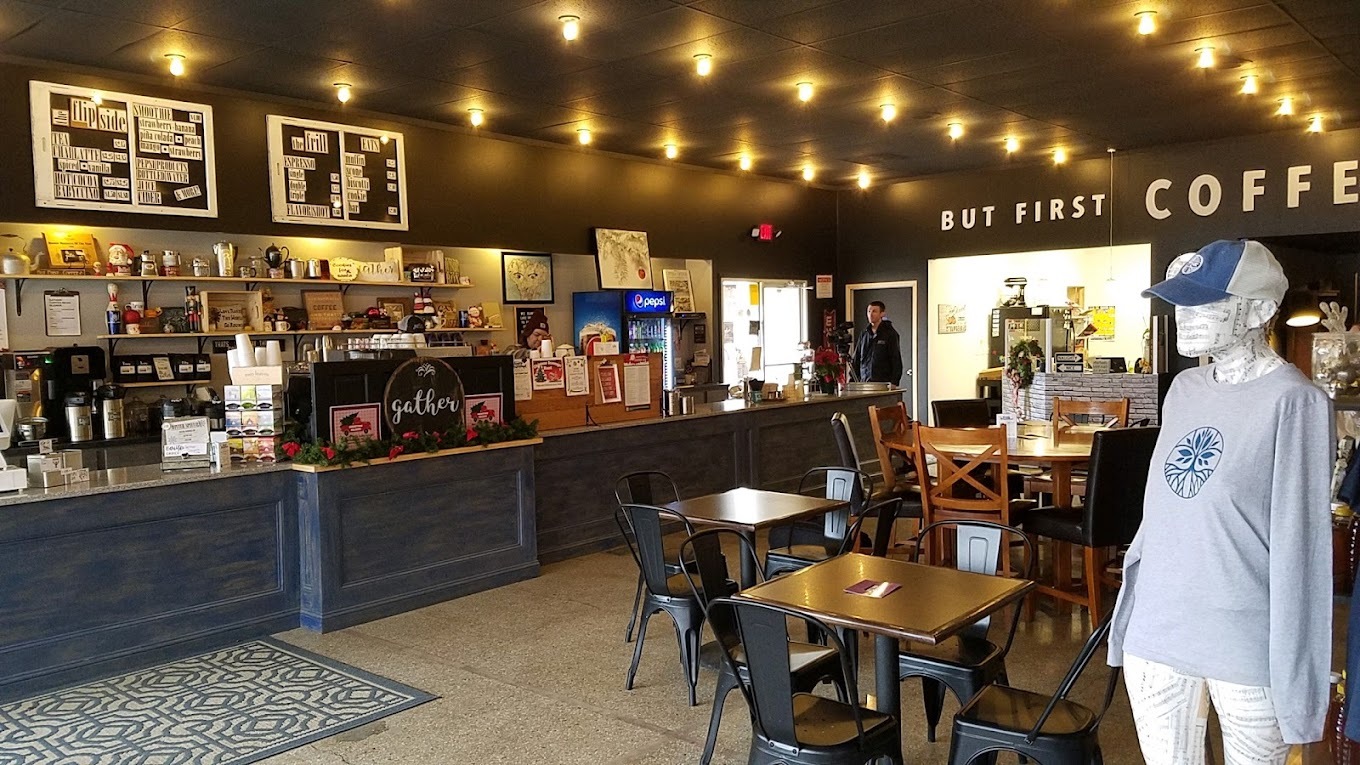A inside view of a cafe with fairy lights on the ceiling, along with seating and a mannequin and clothing for sale.