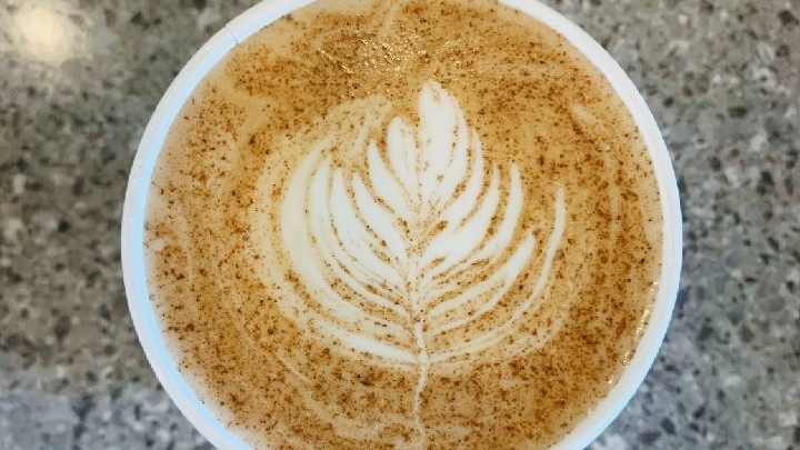 A close up view of a latte with cream art of a leaf.
