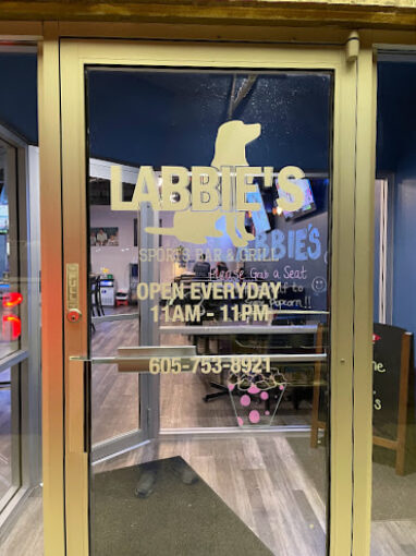 A view of a sports bar door entrance, a glass door with windows and decal on the door reading "Labbies" with a dog logo.