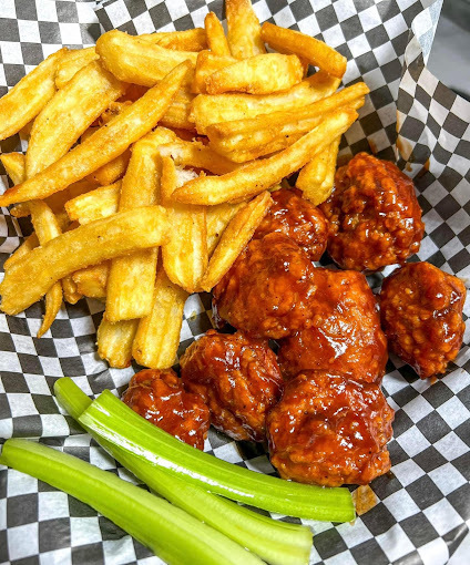 A view of a basket of hot wings, fries and celery.